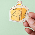 A hand holding a sticker with an illustration of a loaf of bread and the phrase 'Jesus is my daily bread' written on it.